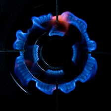 Close-up of a technician inspecting a gas stove for leaks with specialized tools.
