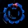A close-up view of a stove burner with a blue flame. The flame forms a ring around the central burner, displaying an intricate pattern. The black metal grates of the stove are visible above the flame, contrasting sharply with the bright blue color.