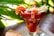 A cocktail glass filled with shrimp cocktail, garnished with shrimp, sliced avocado, and a sprig of fresh herbs. The background features vibrant green leaves, contributing to a tropical ambiance.