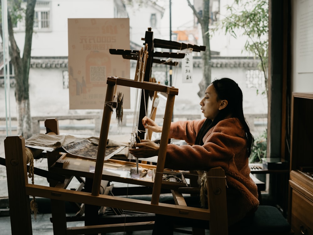 woman in brown and black stripe long sleeve shirt sitting on brown wooden chair