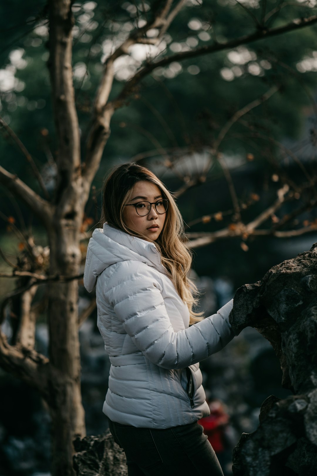 woman in white long sleeve shirt sitting on rock during daytime