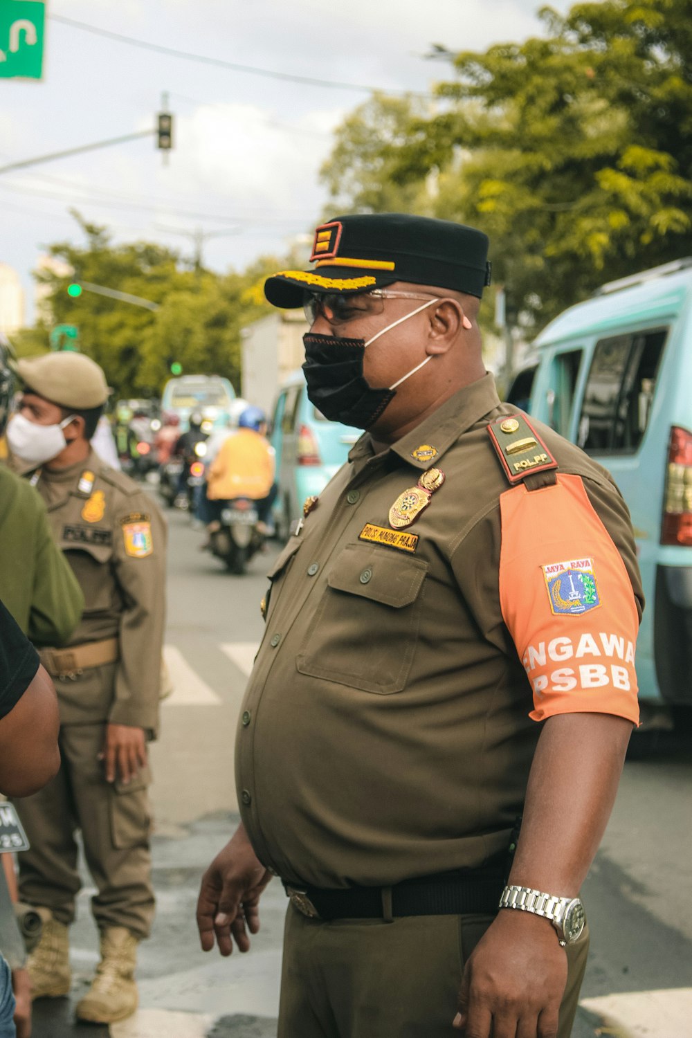 man in green uniform standing near people during daytime