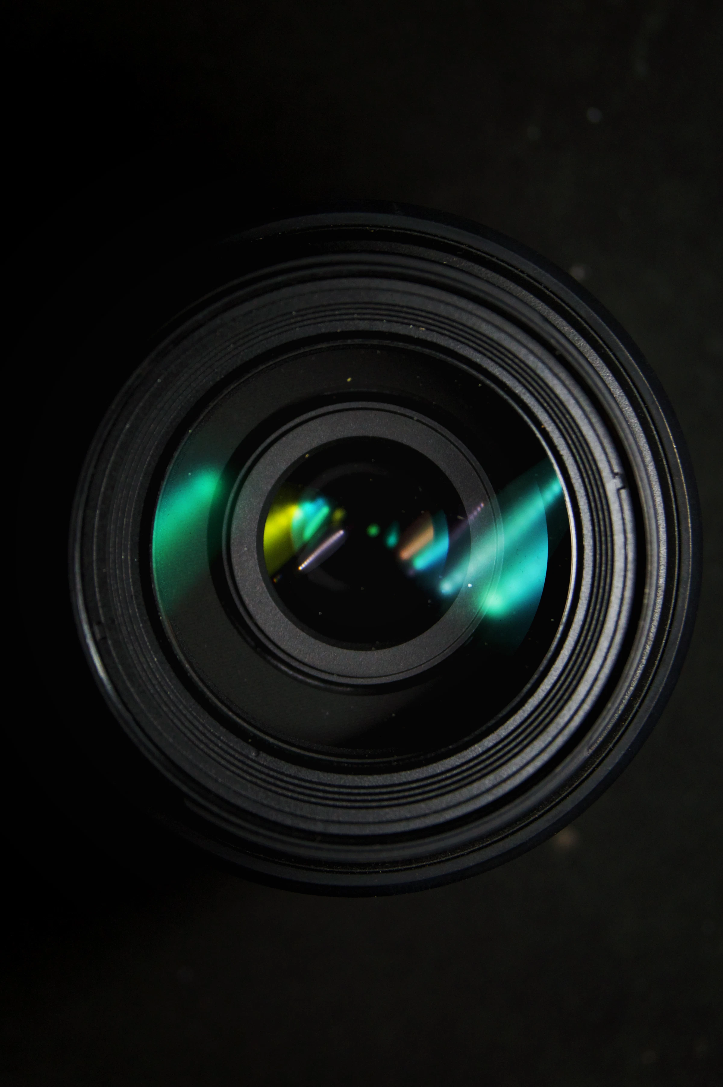 Extreme macro close-up of a camera lens aperture with a green light flare