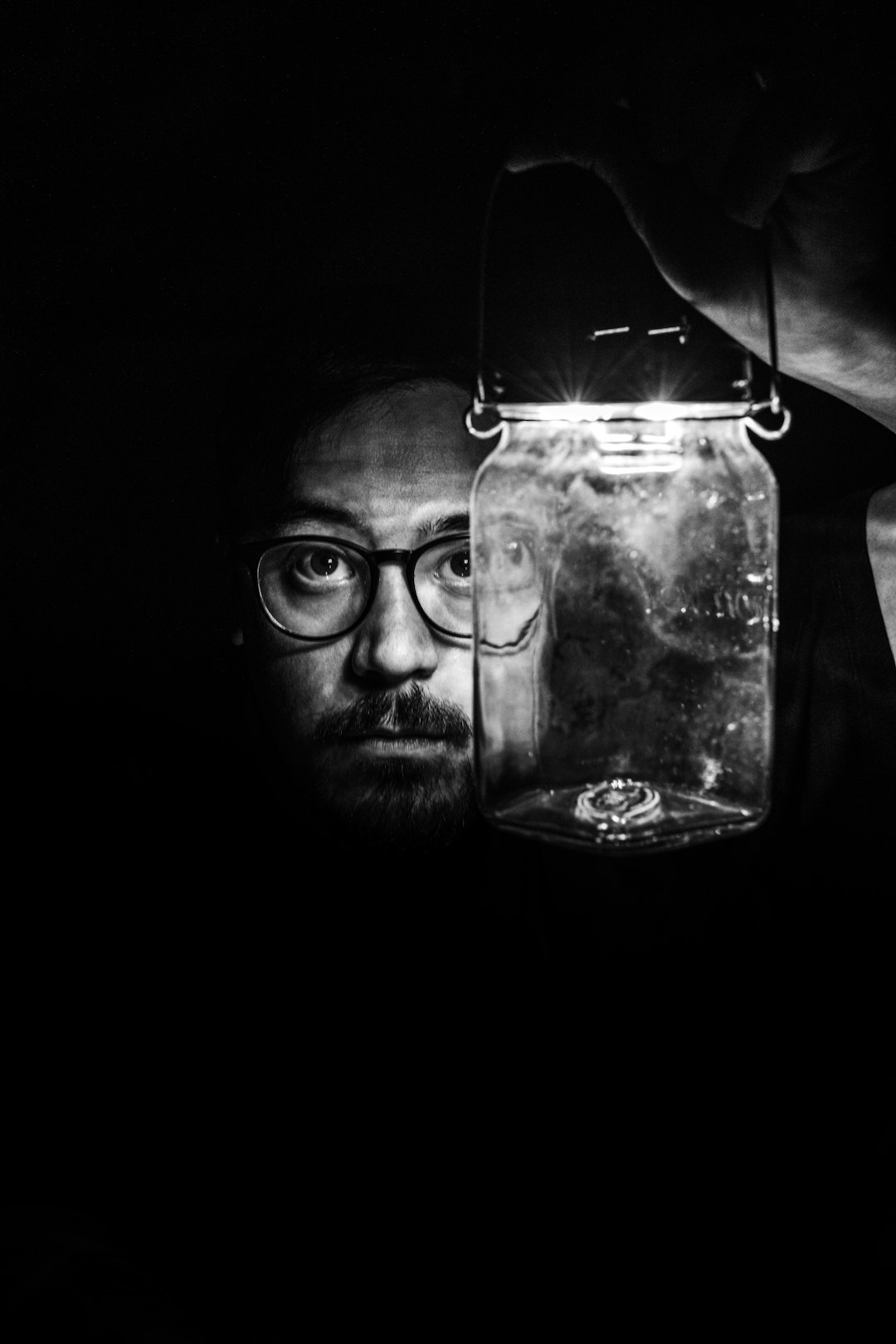 man in black framed eyeglasses holding clear glass jar