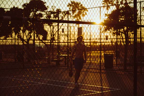 Morning sunlight casting long shadows on a freshly swept tennis court at raquetaviva