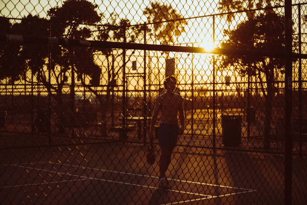 man in black jacket standing beside fence during daytime