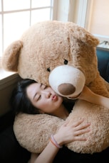 girl hugging brown bear plush toy