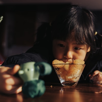 Close-up of a child's hands reaching for sliced oranges and kiwi arranged on a wooden table.