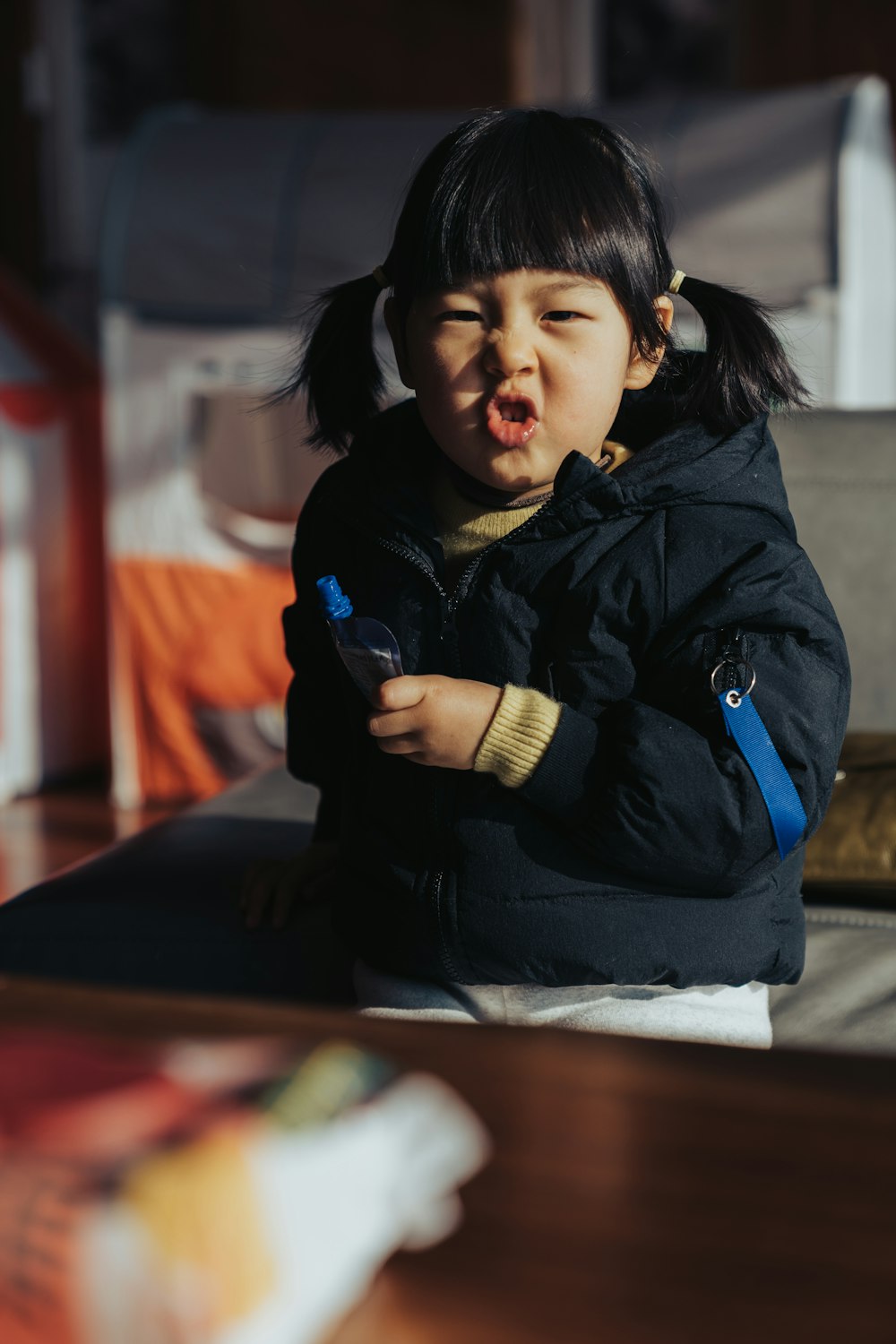 girl in black jacket sitting on brown wooden table