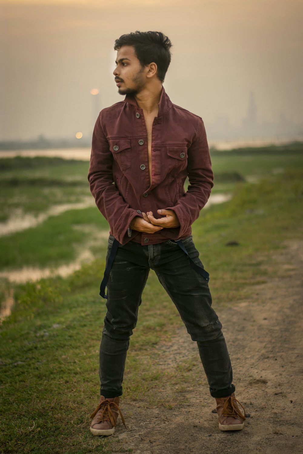 man in brown button up jacket and black pants standing on green grass field during daytime