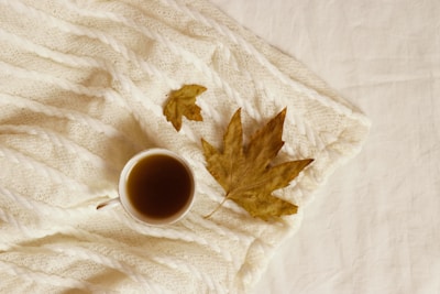 A cozy autumn scene with colorful leaves and a warm drink.