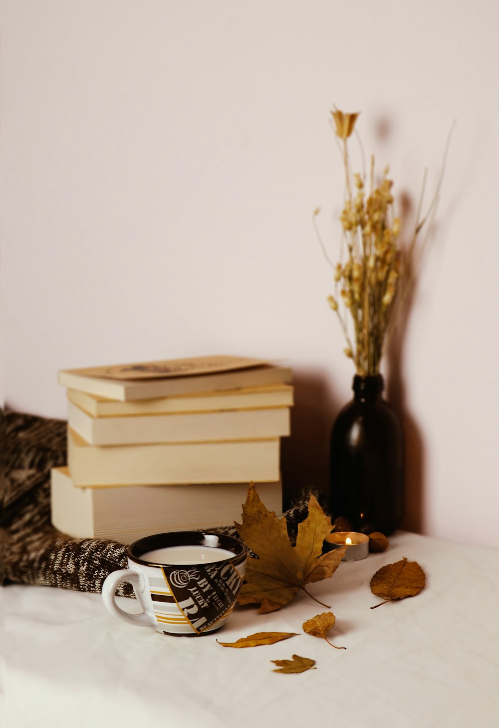 black and white ceramic mug beside brown wooden book