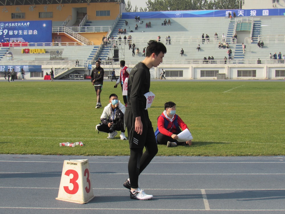 man in black and white long sleeve shirt and black pants sitting on green grass field