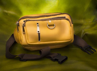 A vibrant mini waist pack in bright coral resting on a sunlit wooden bench with summer accessories around.