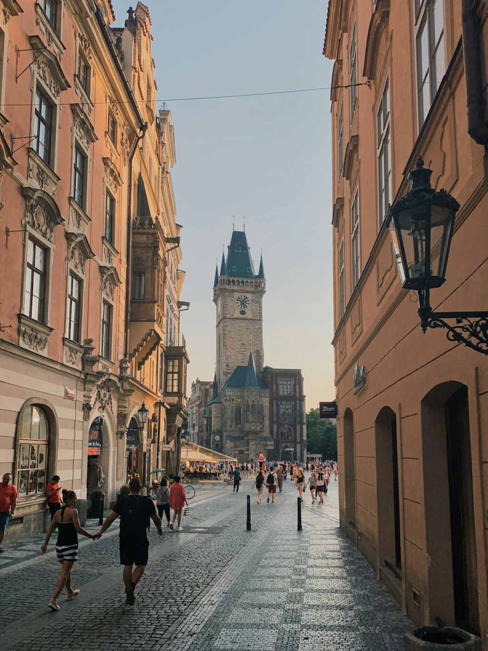 a group of people walking down a street next to tall buildings