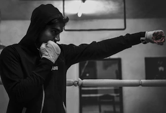 Athlete wearing a stylish hoodie in motion during a boxing workout in an industrial gym.