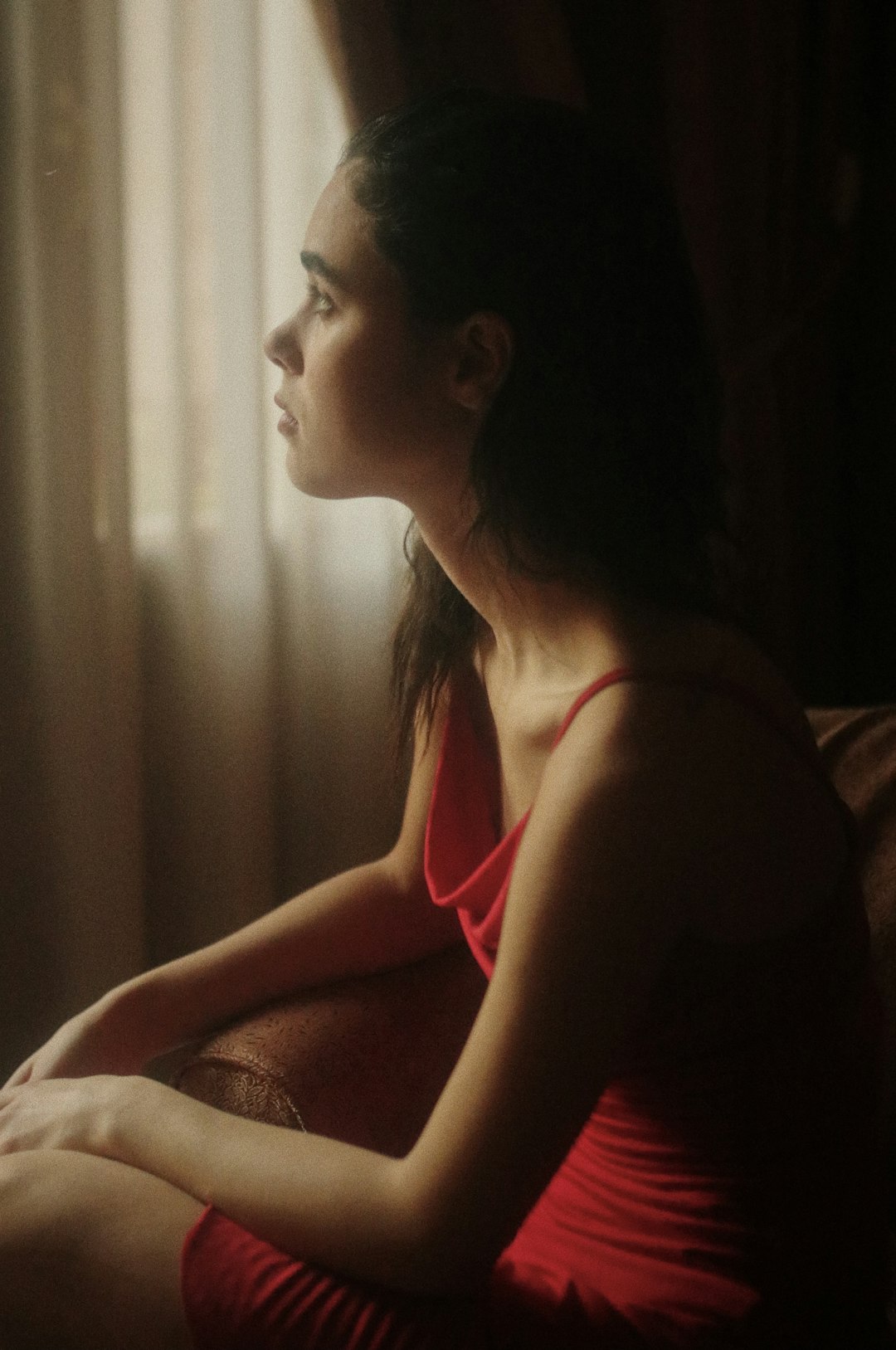 woman in red tank top sitting on bed