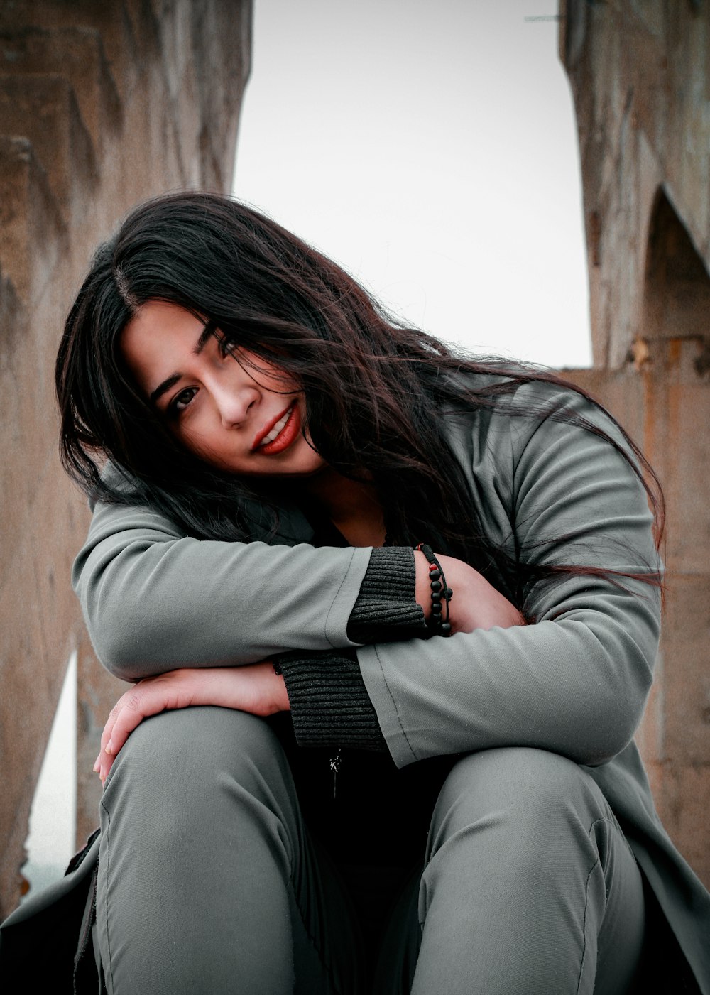 woman in gray long sleeve shirt and black pants sitting on brown wooden bench