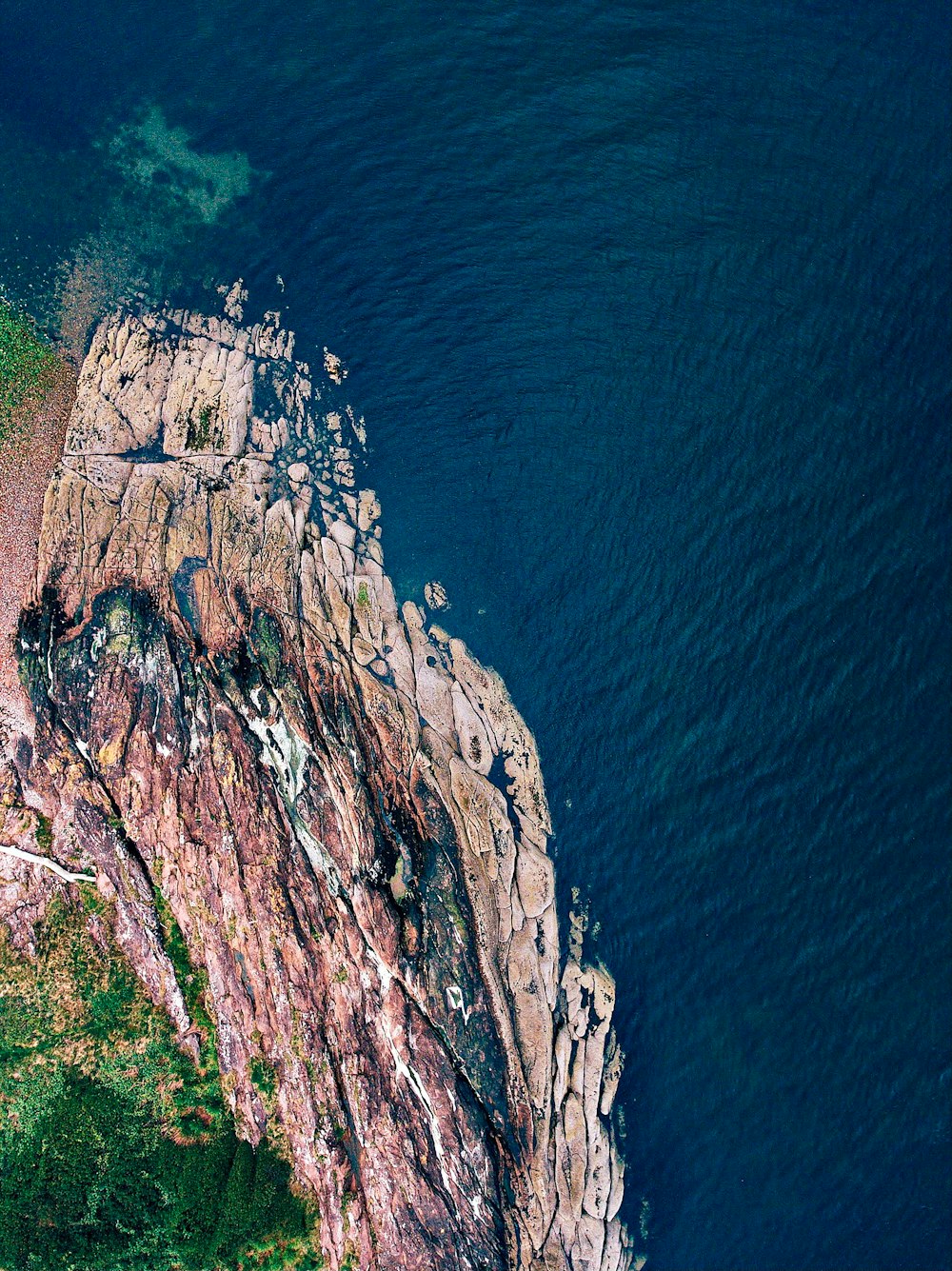 brown rocky mountain beside blue sea during daytime