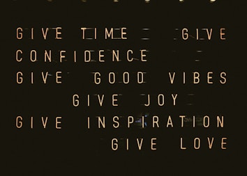 A series of motivational phrases are displayed in neon-style text against a dark background. The phrases include 'give time', 'give confidence', 'give good vibes', 'give joy', 'give inspiration', and 'give love'. The words are arranged in a structured, grid-like format, creating a visually impactful and positive message.