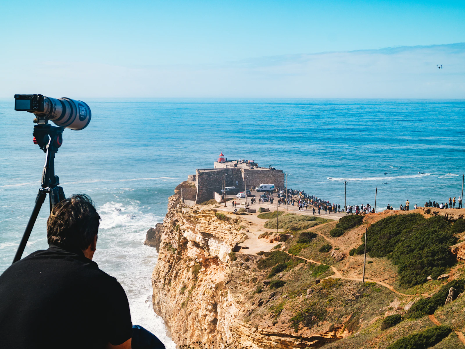 A creator setting up a camera on a clifftop above the sea, filming a coastal destination