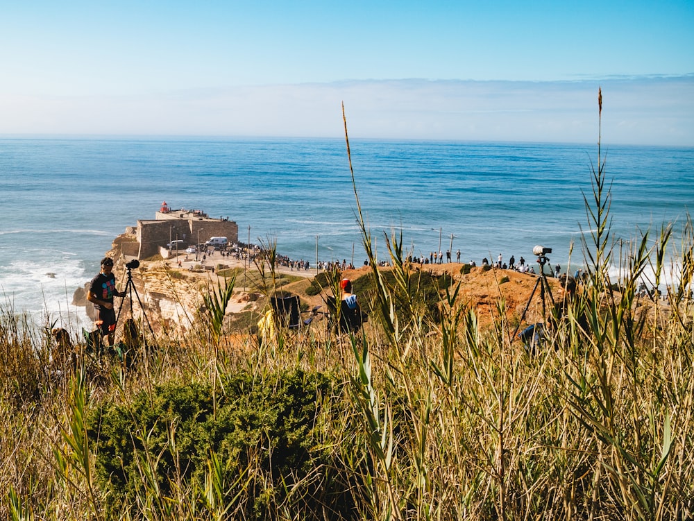 people on brown rock formation near body of water during daytime