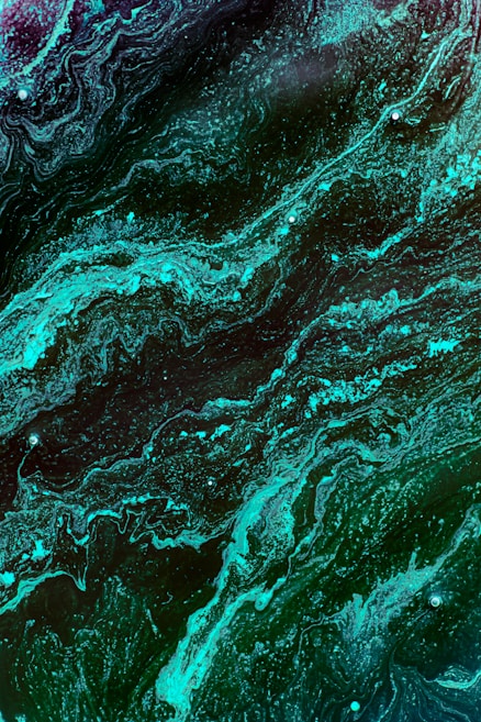 Swirling patterns of rich turquoise and teal hues blend with darker shades, creating an abstract and fluid design. The flowing lines and textures resemble a marbled effect, invoking a sense of depth and movement.