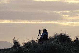 silhouette of man and woman sitting on grass during sunset