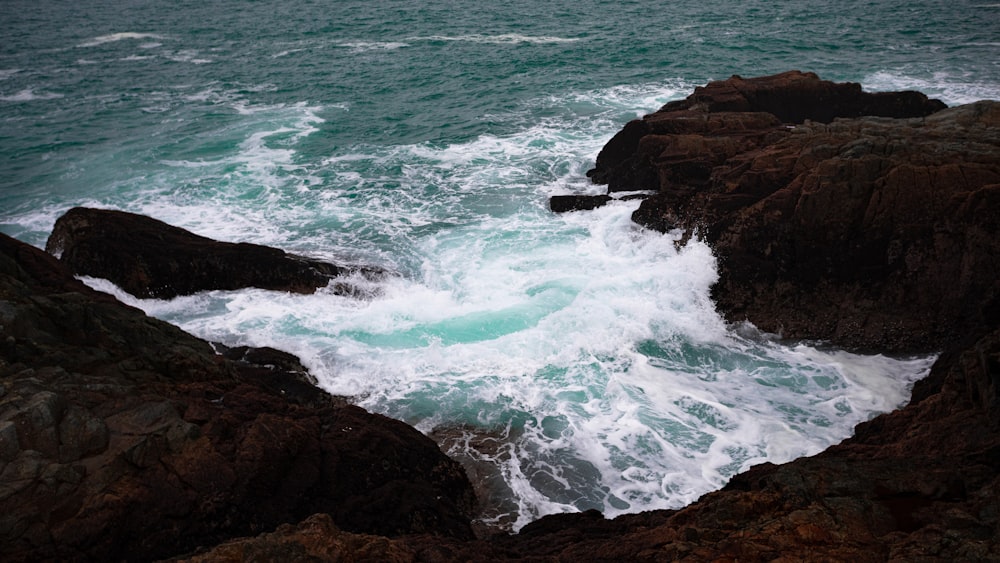 ocean waves crashing on brown rock formation during daytime