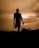 A silhouette of a person standing on one leg, using crutches, against a warm, dramatic sunset or sunrise sky. The surrounding landscape is slightly visible with outlines of plants and hills.