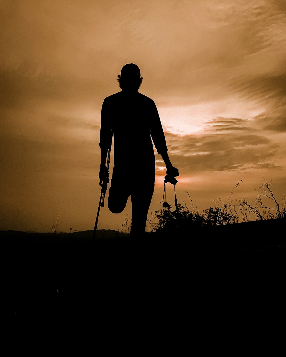 silhueta do homem em pé no campo de grama durante o pôr do sol