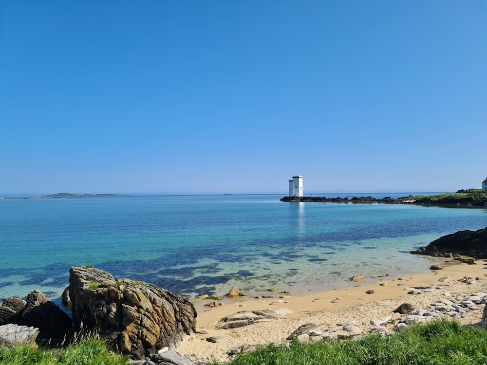 white lighthouse on brown sand near body of water during daytime