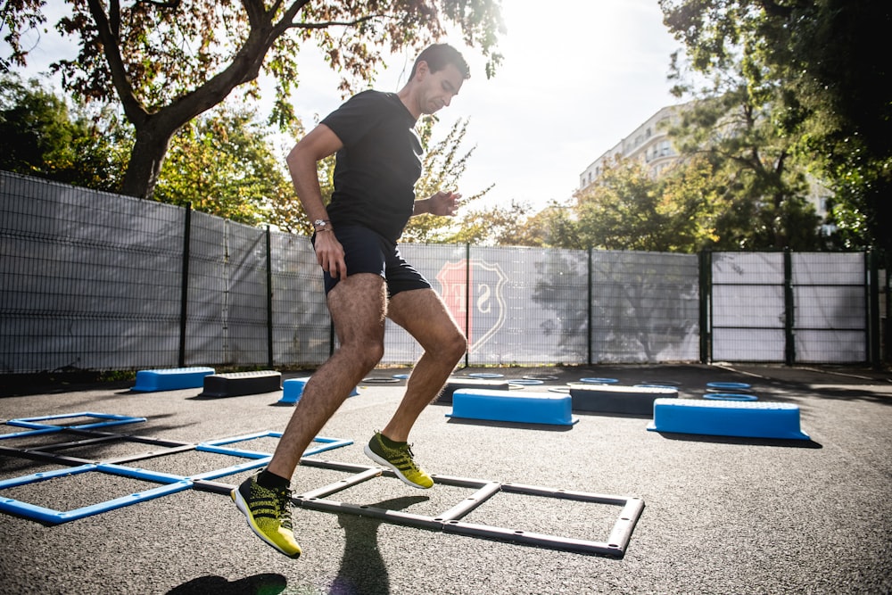 man in gray t-shirt and black shorts running on yellow and black skateboard during daytime