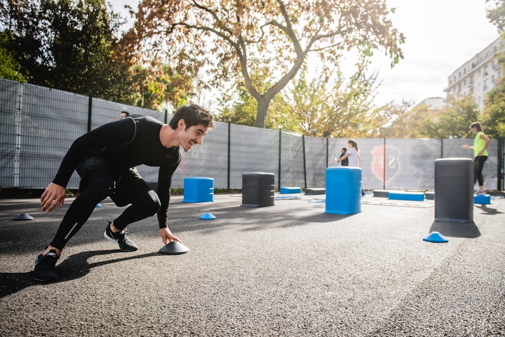 boy in black long sleeve shirt and blue pants playing with blue plastic container during daytime