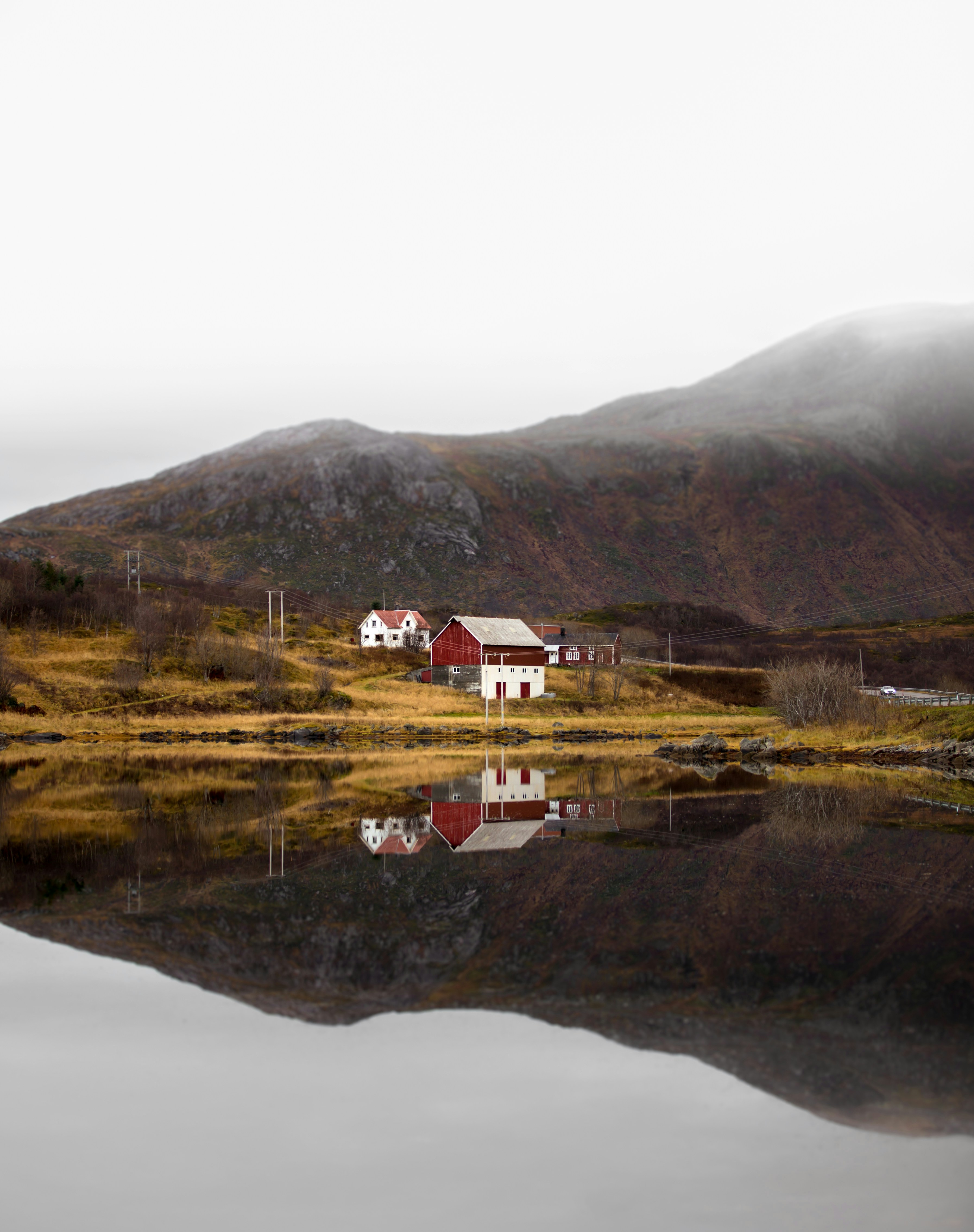 white and red house near lake and green mountain