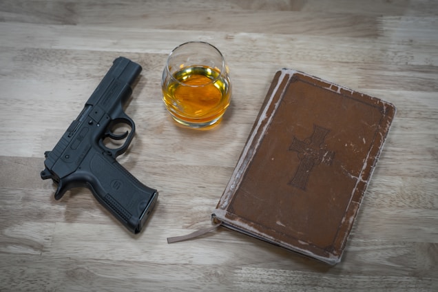 A vintage firearm blueprint spread across a wooden desk with a pair of reading glasses resting nearby.