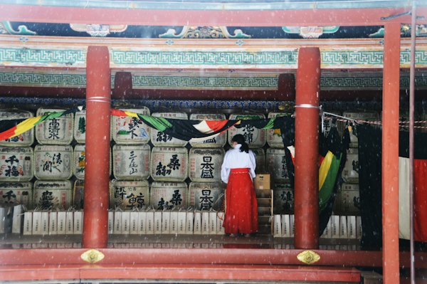Woman in white dress standing on red wooden door — Nikko, Japan