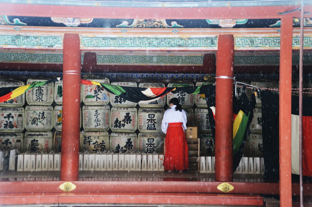 woman in white dress standing on red wooden door