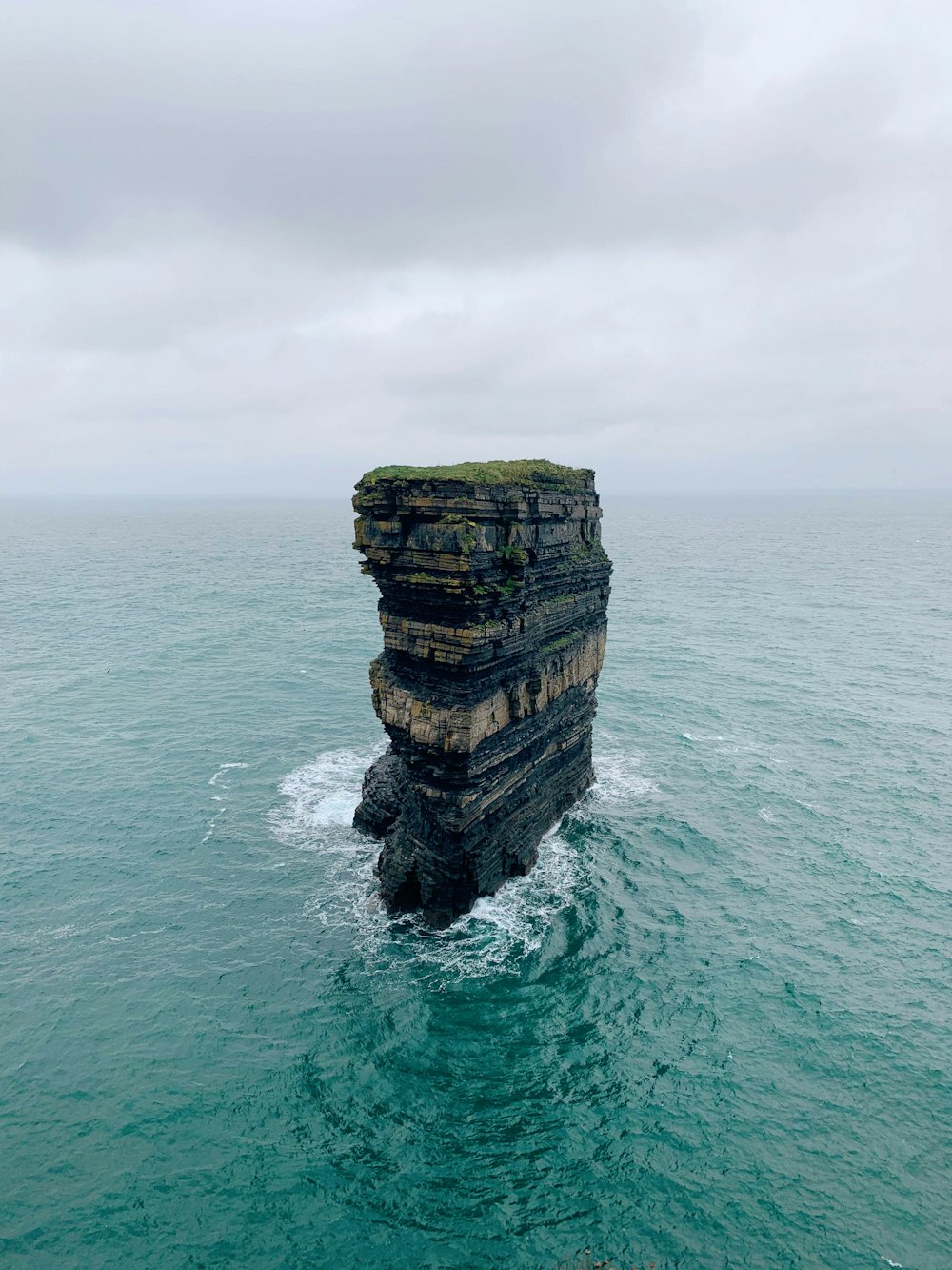 brown rock formation on body of water during daytime