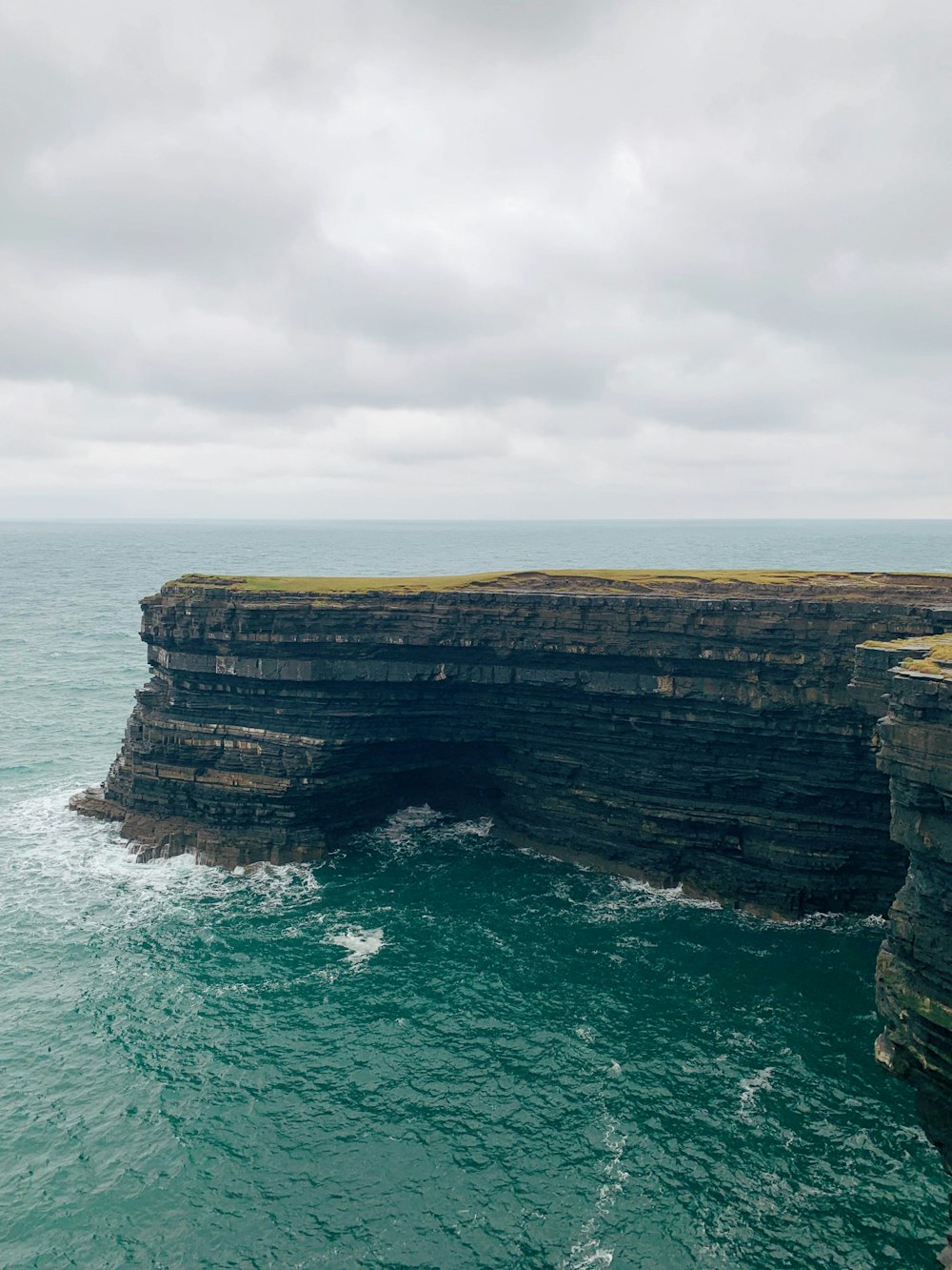 brown rock formation beside body of water during daytime