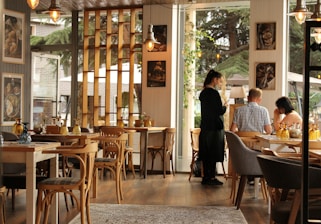 woman in black long sleeve shirt standing beside brown wooden table