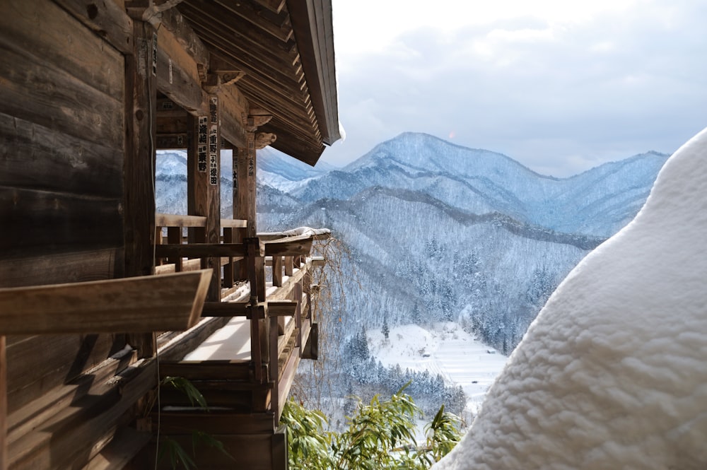 brown wooden house near snow covered mountain during daytime