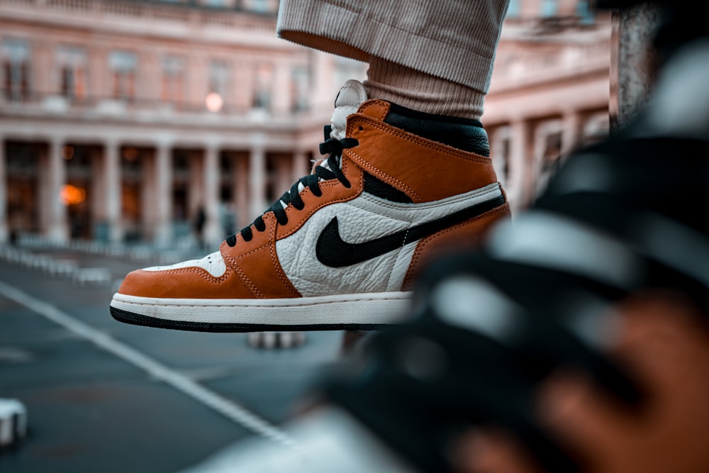 person wearing brown and white nike high top sneakers