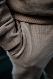 Close-up view of beige corduroy pants, highlighting the texture and detail of the fabric with a hand in the pocket.