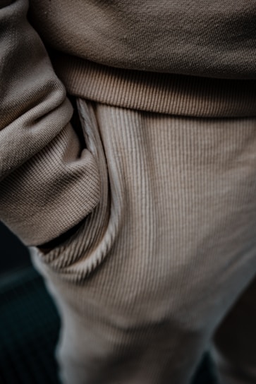Close-up view of beige corduroy pants, highlighting the texture and detail of the fabric with a hand in the pocket.