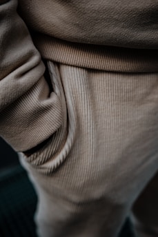 Close-up view of beige corduroy pants, highlighting the texture and detail of the fabric with a hand in the pocket.