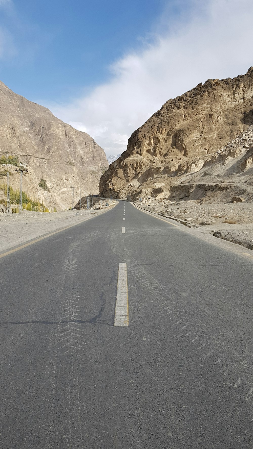 Strada di cemento grigia vicino alla montagna rocciosa marrone sotto il cielo bianco durante il giorno