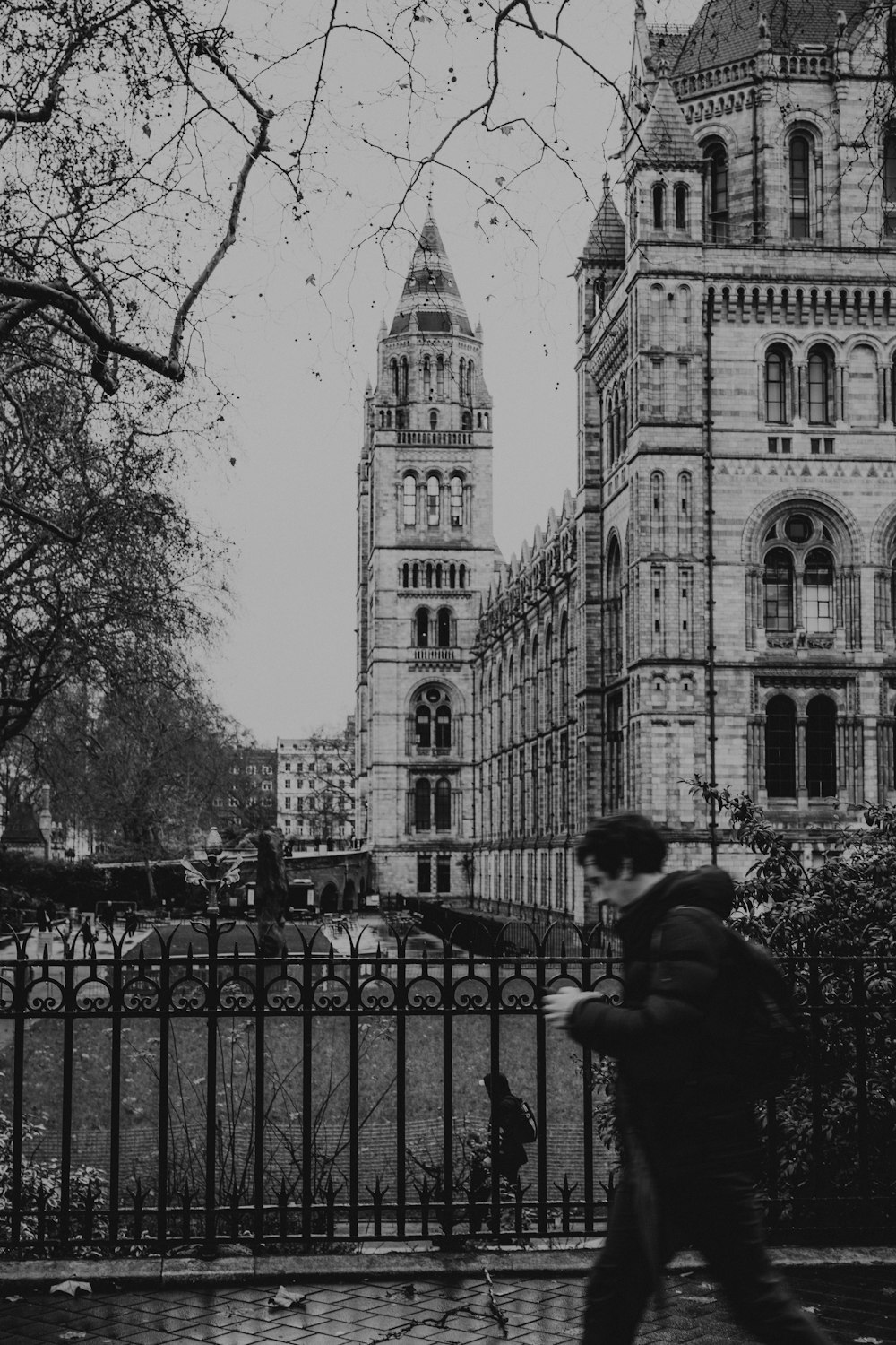foto em tons de cinza do homem na jaqueta sentado no banco perto do edifício
