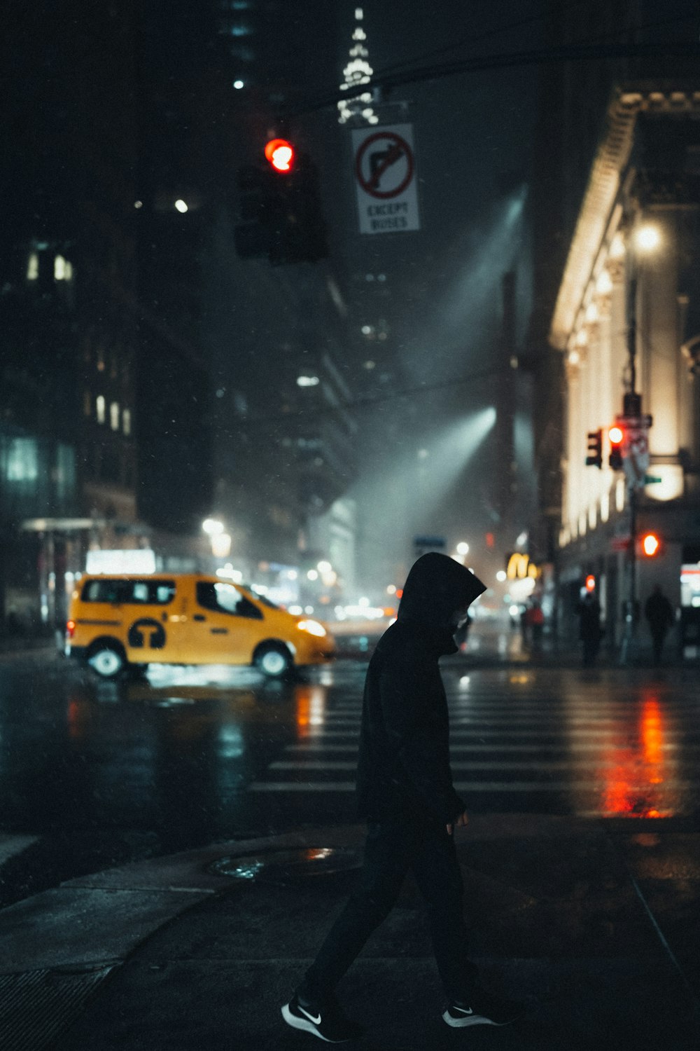 pessoa em capuz preto em pé na rua durante a noite