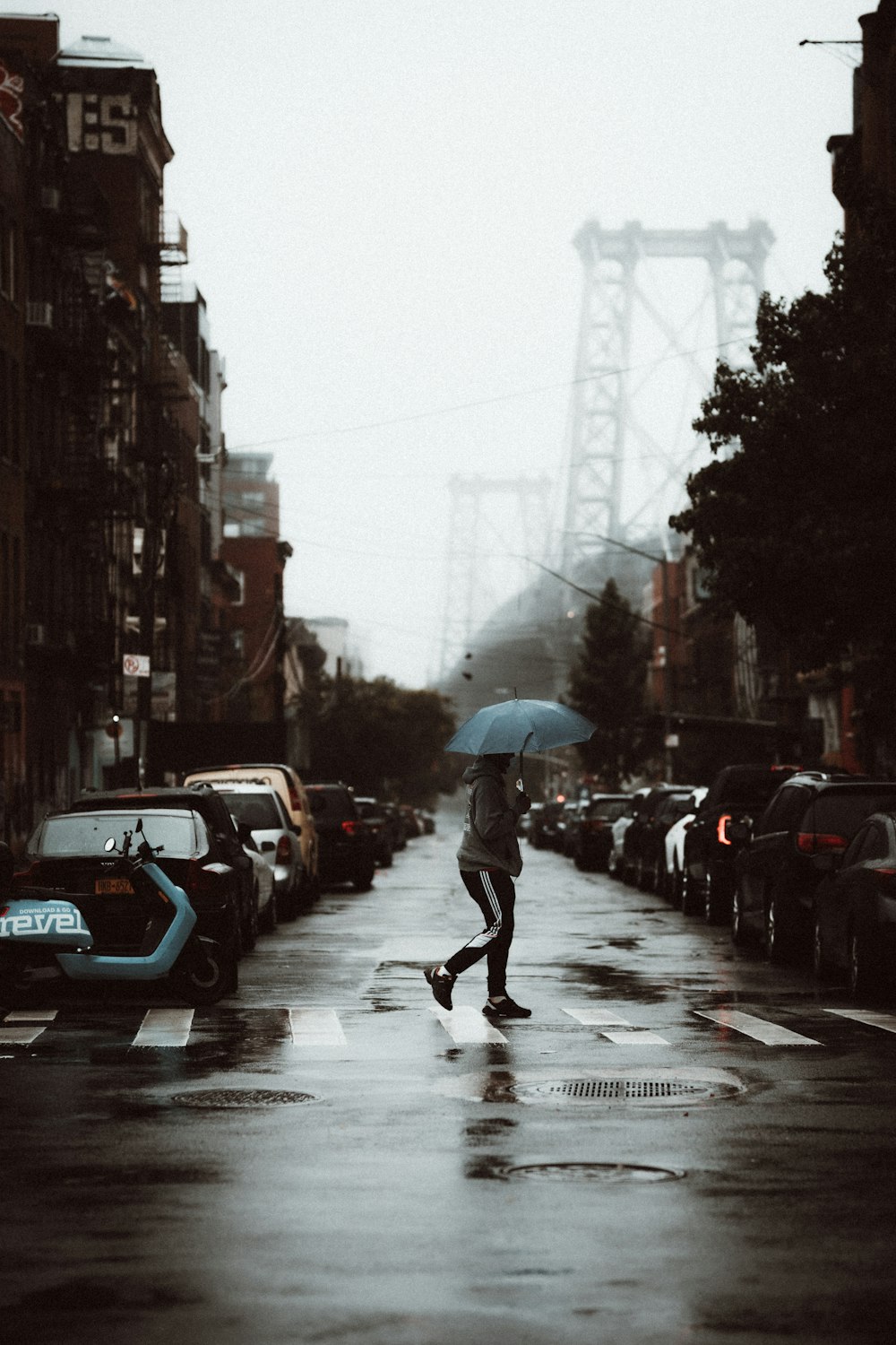 person in black jacket and black pants holding umbrella walking on street during daytime